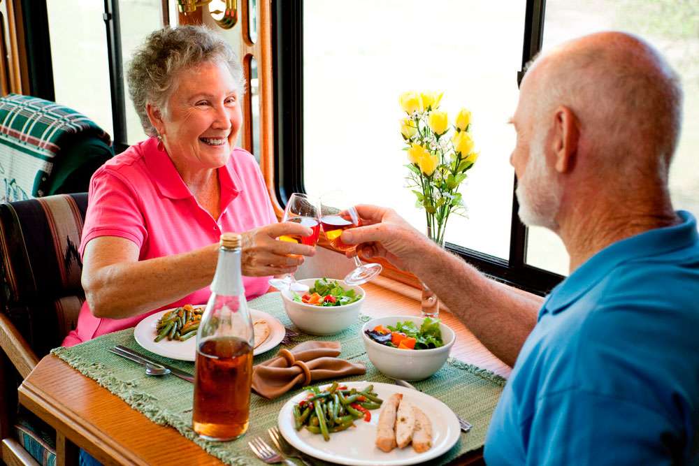Beneficios de los menús a domicilio para mayores Una pareja mayor brinda antes de comenzar a comer