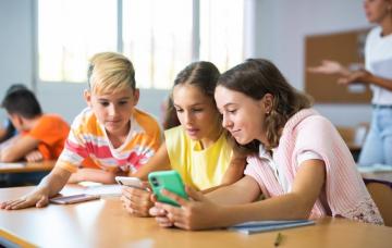 Niños usando grupos de whatsapp en sus smartphones Grupo de escolares consultando whatsapp en sus teléfonos en el colegio
