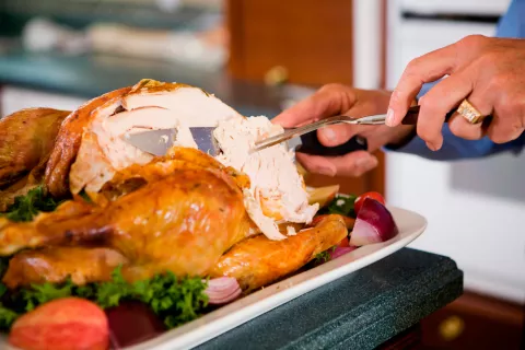 Recomendaciones de consumo de pavo en la dieta Un hombre corta una tajada de un pavo asado