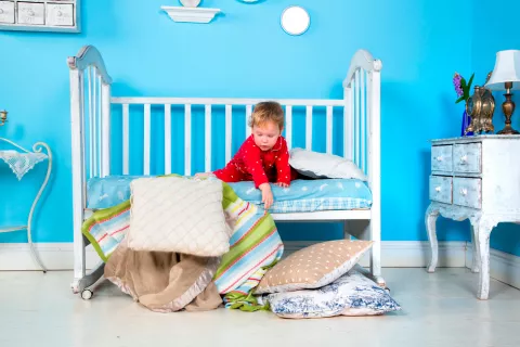 Cuándo y cómo pasar al niño de la cuna a la cama Niño bajándose de la cuna