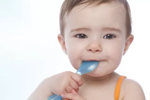 Regurgitaciones y vómitos del bebé Primer plano de un bebé mordiendo una cuchara