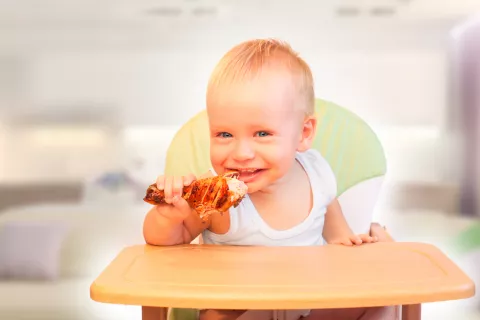 Los niños deben comer carne, advierten los expertos Un niño pequeño muerde un muslo de pollo