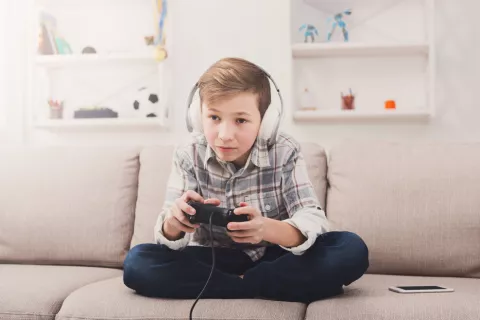 Los jugadores de videojuegos tienen más riesgo de tinnitus y sordera Niño jugando a videojuegos con los auriculares puestos