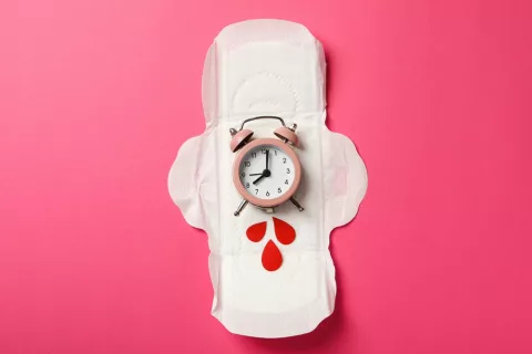 Un reloj interno regula el ciclo menstrual, sincronizado también por la luna Un reloj somre una compresa simbolizando el tiempo para la próxima mestruación
