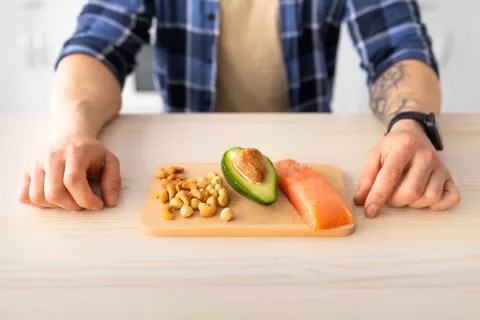 Revelan qué incluir en la dieta para ayudar a frenar el cáncer de próstata Un hombre sentado en una mesa con alimentos ricos en omega 3 delante.