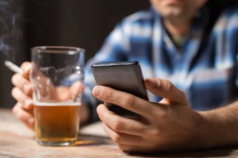 Hábitos poco saludables han contribuido a que se frene la esperanza de vida en Europa Hombre fuma sentado a una mesa con una cerveza y consultando su móvil