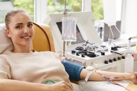 La donación de sangre frecuente produce beneficios genéticos frente al cáncer Mujer joven sonríe mientras dona sangre