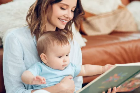 Los bebés pueden codificar y almacenar recuerdos antes de lo que se creía Madre muestra a su bebé un libro con imágenes